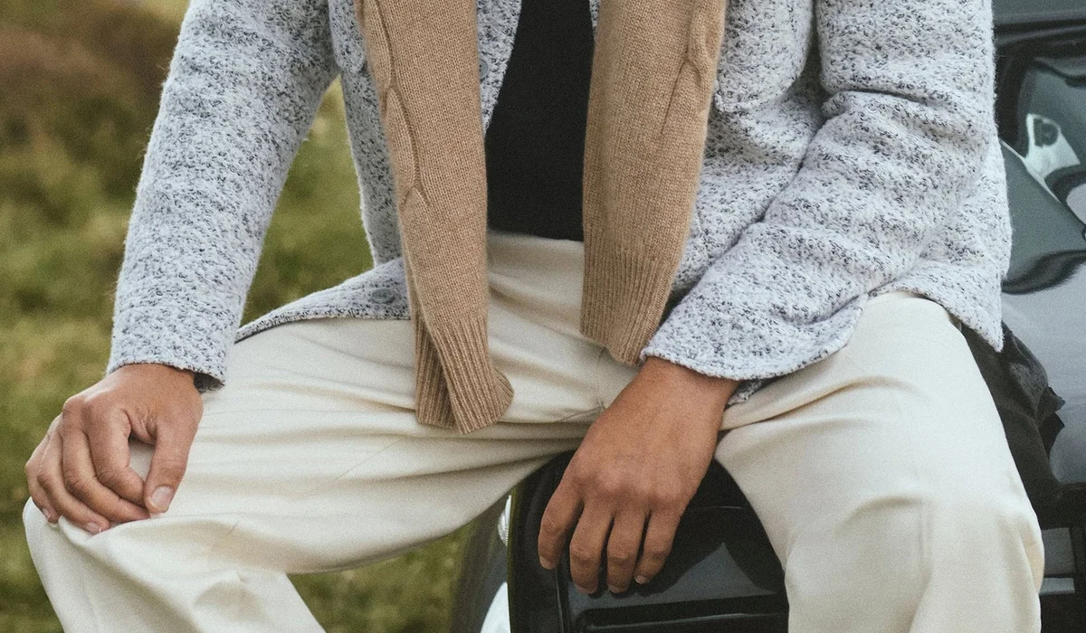 Man in cream trousers and knit scarf outdoors in fall