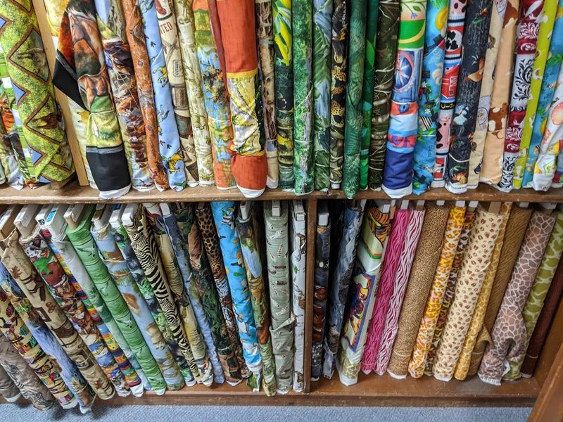 Shelves packed with rolls of colorful patterned cotton fabric