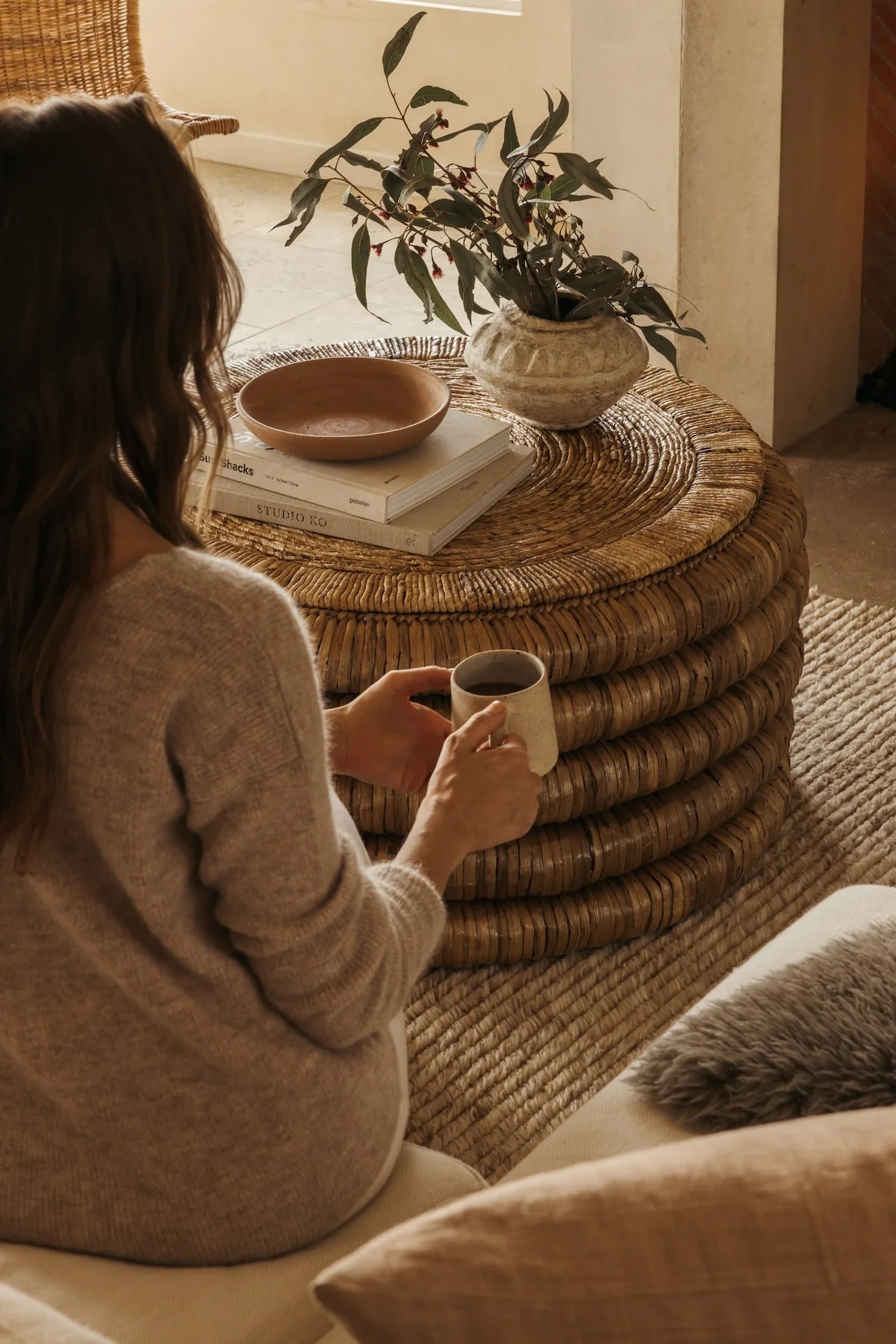 Woman with a warm drink by a bright window, ready for a movie night